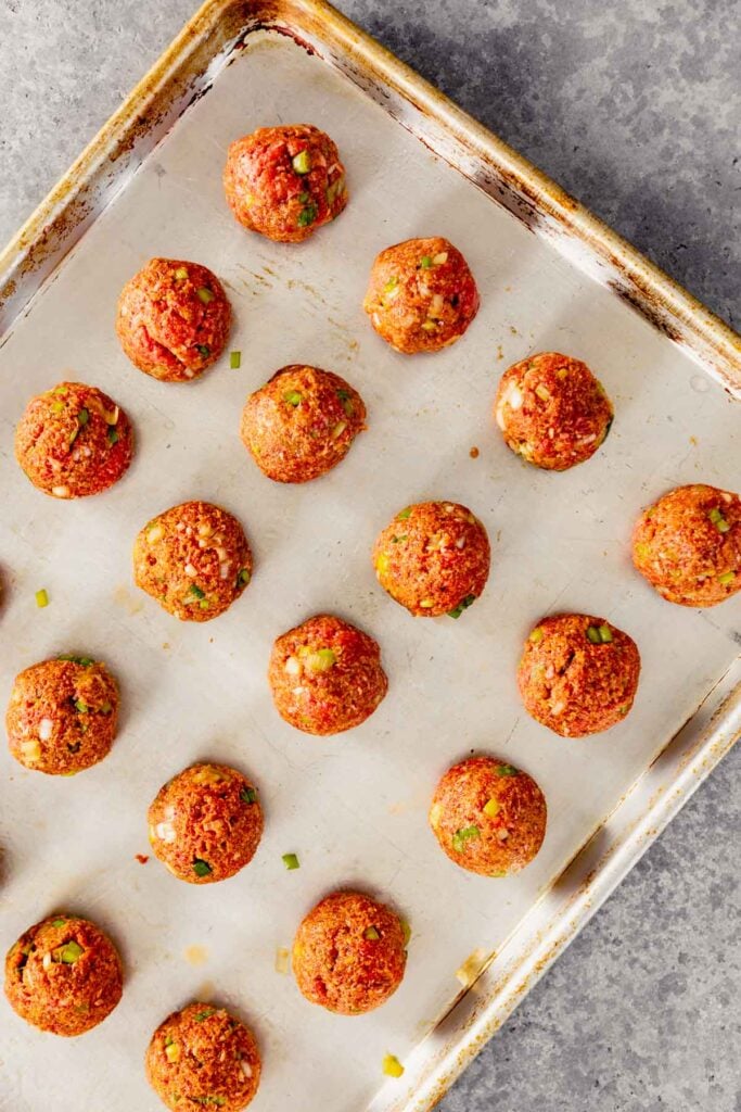 un-cooked meatballs on a baking sheet