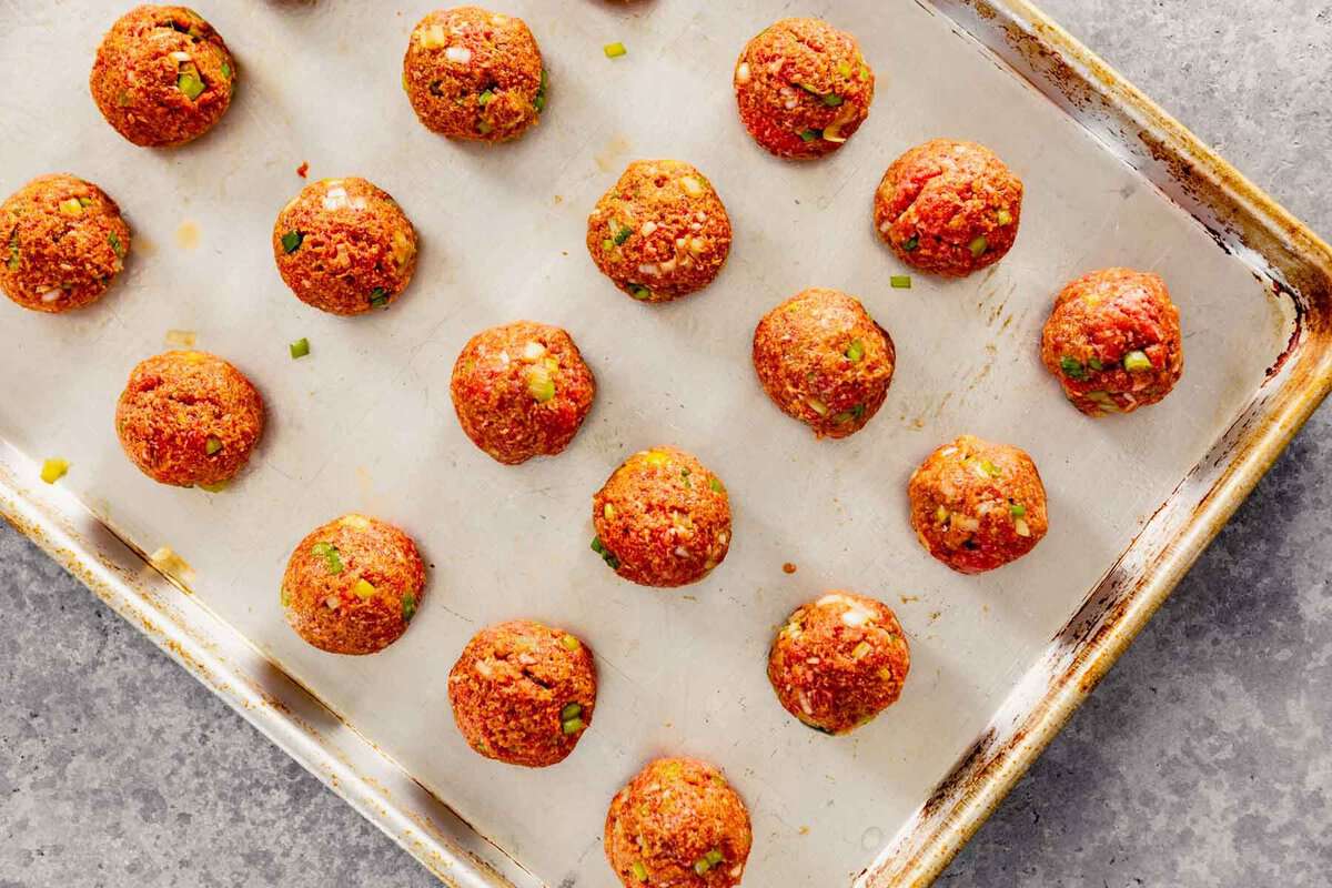 un-cooked meatballs on a baking sheet