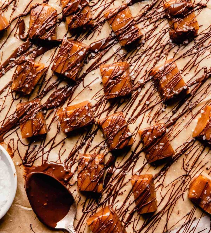 homemade caramels drizzled with chocolate set on brown parchment paper