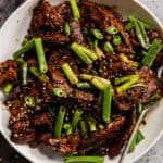 pork bulgogi in a large white bowl with large pieces of green onion and serrano