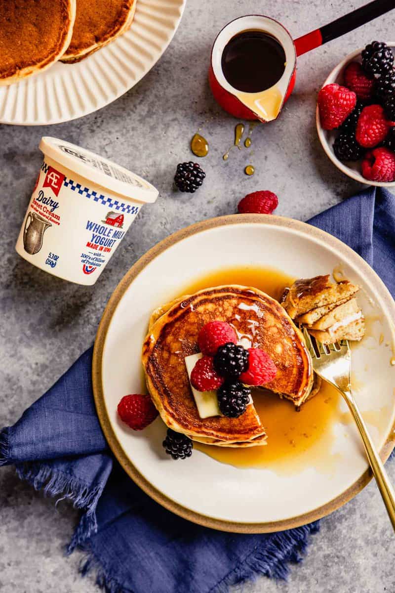 yogurt pancakes on a plate topped with berries and maple syrup