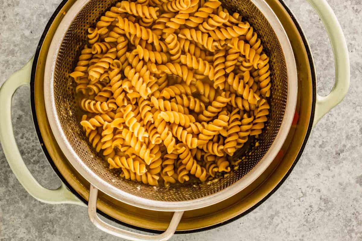 pasta cooking in a soup with a colander set in it