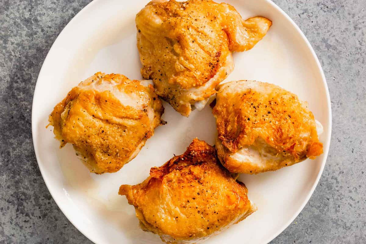 crispy fried chicken thighs on a large white plate.