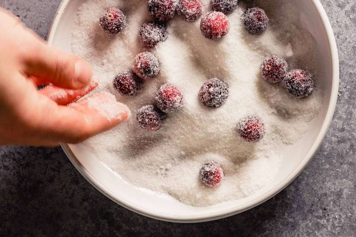 a hand tossing cranberries in sugar