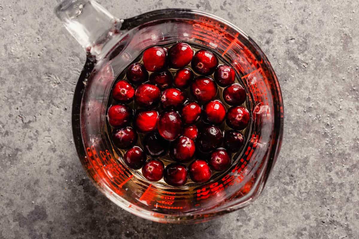 fresh cranberries in a sugar syrup in a liquid measuring cup