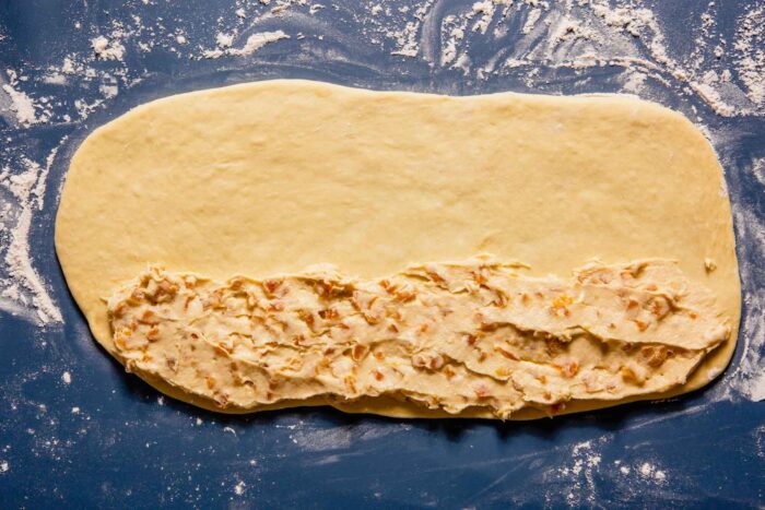 rectangle of dough with creamy filling spread long the bottom of the dough