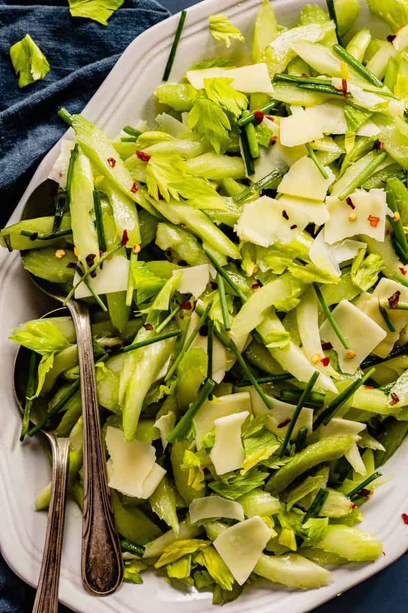 sliced celery salad with cheese and chives on a large white oval plate
