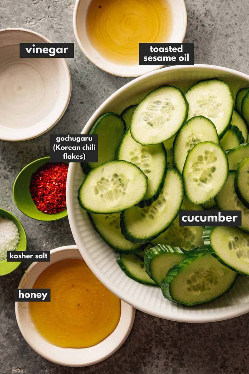 sliced cucumber, chili flakes, honey, sesame oil, salt and vinegar measured out in bowls and set on a counter