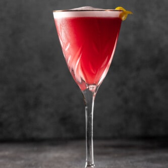 pink cocktail in a martini glass with a layer of white foam on top