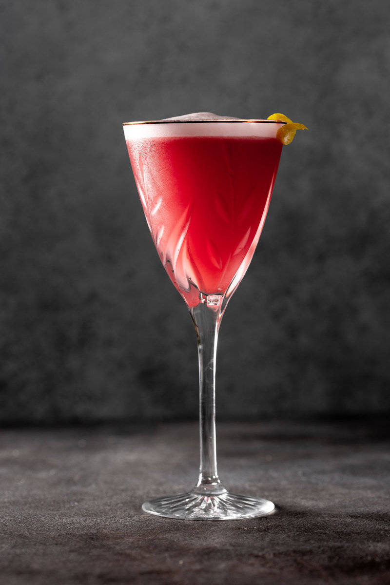 pink cocktail in a martini glass with a layer of white foam on top
