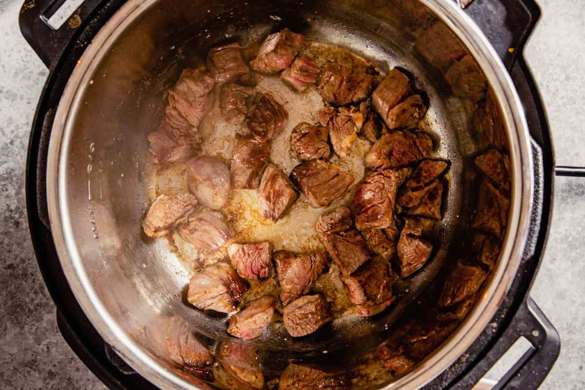 chunks of beef cooking in an instant pot