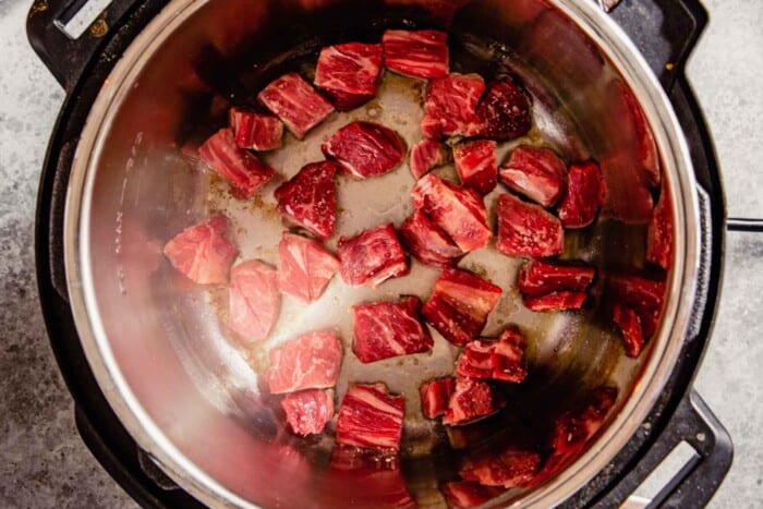 chunks of beef cooking in an instant pot