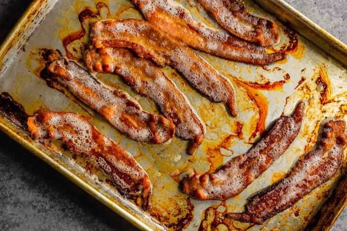 cooked bacon sliced on a baking sheet