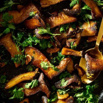 slices of king oyster mushrooms in a cast-iron skillet with parsley and lemon zest