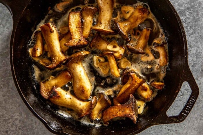 slices of king oyster mushrooms frying in a cast-iron skillet