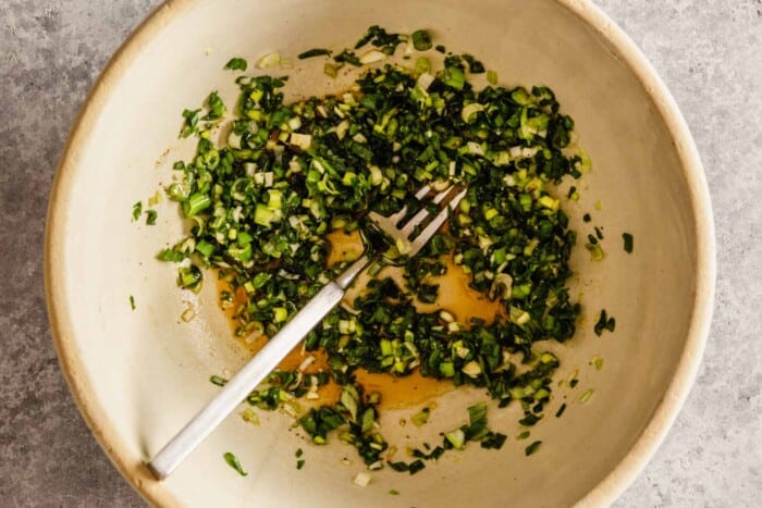 minced scallions in a light brown bowl with a fork sitting in it