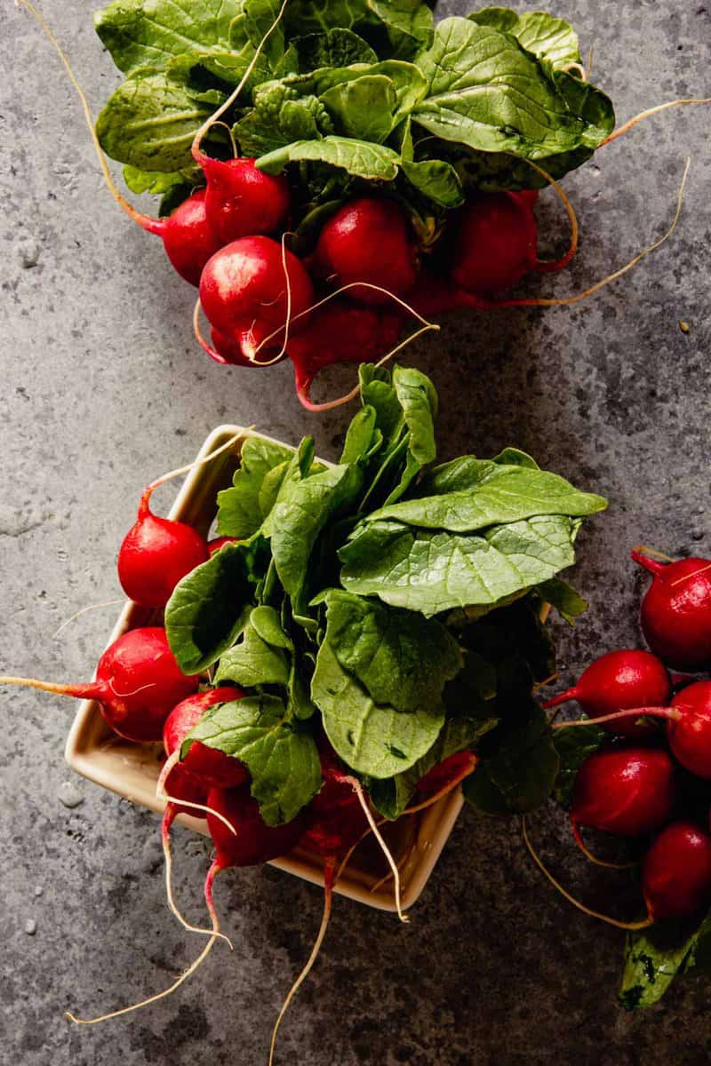 radishes with greens in a colander on a counter