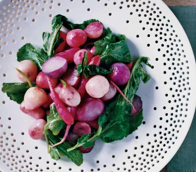 roasted radishes with their greens on a white plate