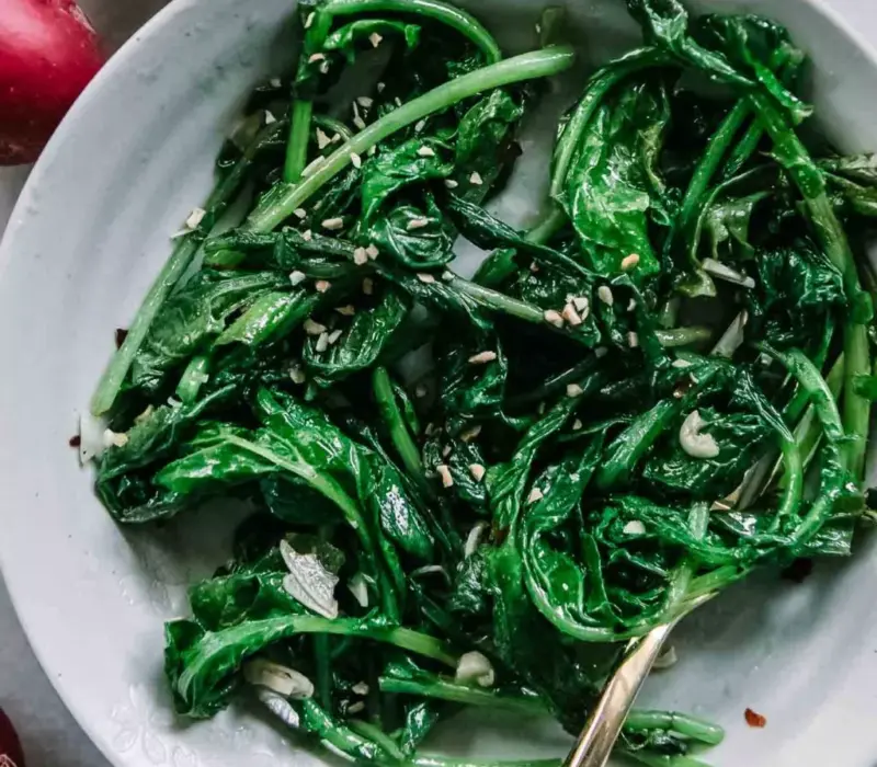 Sauteed radish greens in a large white bowl
