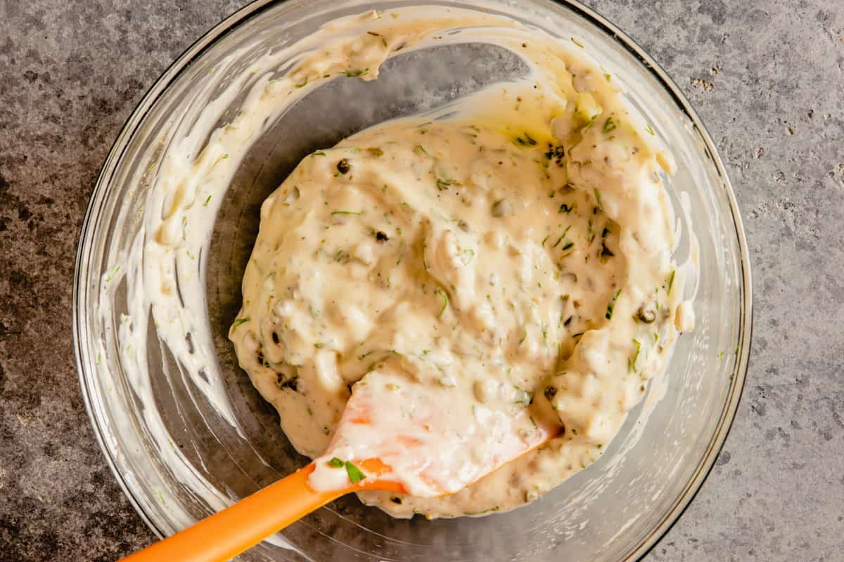 tartar sauce in a glass bowl with an orange spatula set in it
