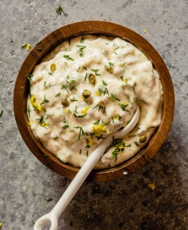 tartar sauce in a small wooden bowl with a white glass spoon