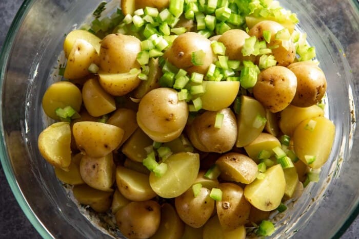 halved baby gold potatoes and chopped celery in a large glass bowl