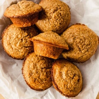 muffins piled into a bowl lined with white parchment paper