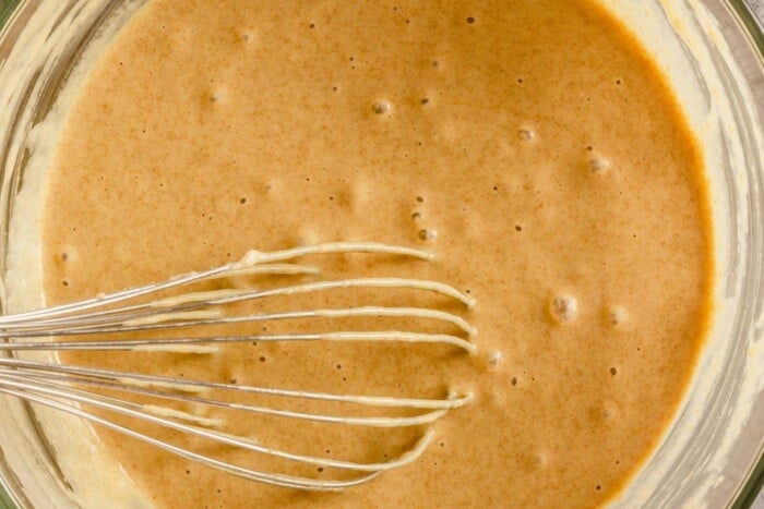 bubbly caramel-colored batter in a large glass bowl with a whisk