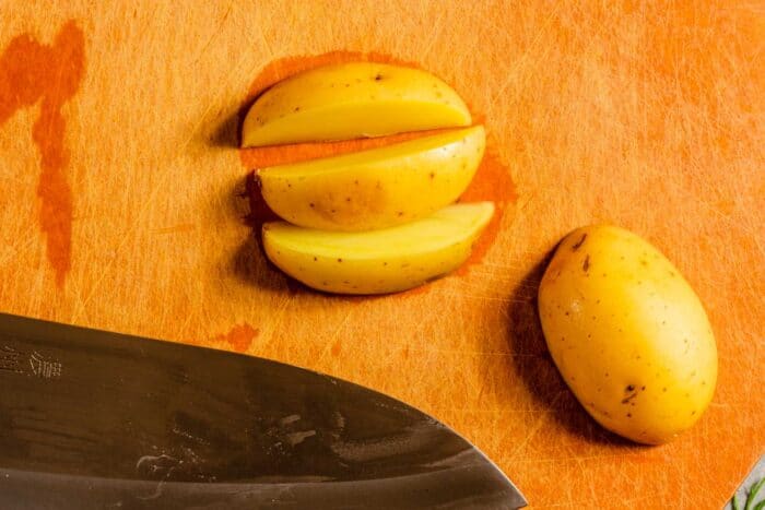 potato cut into wedges on a wood cutting board