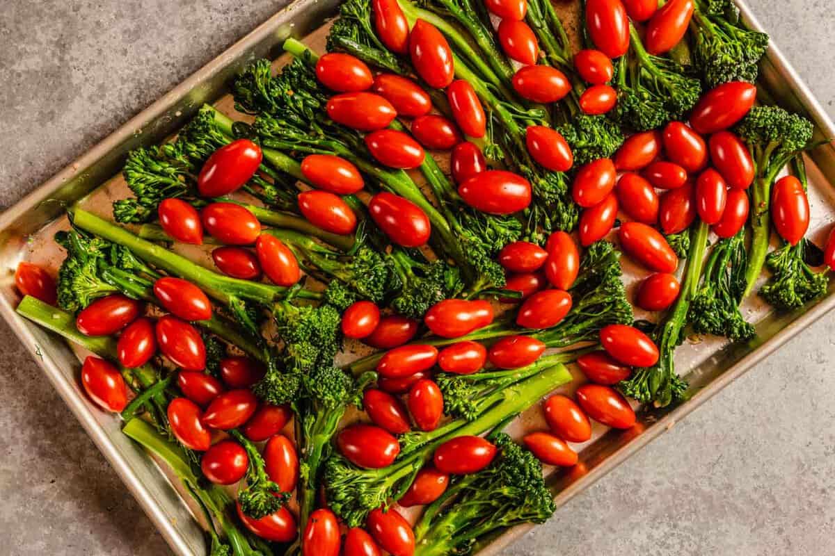 broccolini and tomatoes on a baking sheet