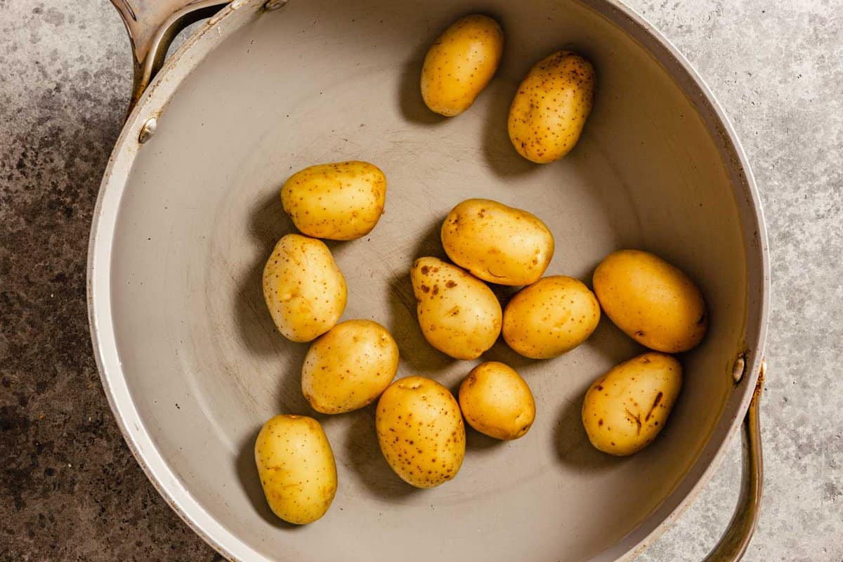baby gold potatoes in a large saute pan filled with water