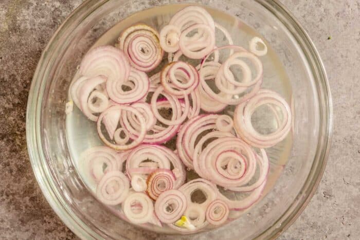 thin slices of shallot in a small glass bowl filled with water