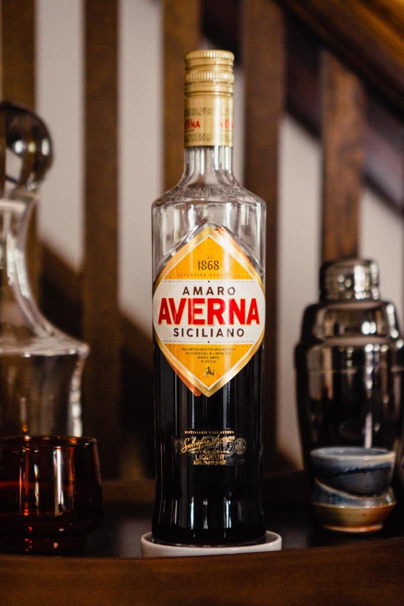bottle of averna amaro set on a dark wood cabinet