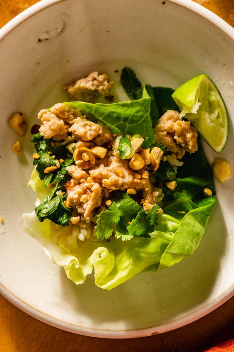 ground chicken and herbs in a lettuce cup on a white plate