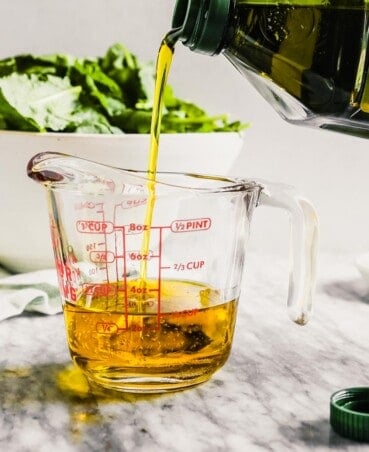 olive oil getting poured into a liquid measuring cup