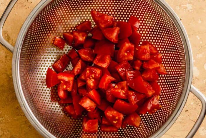 chunks of tomato in a colander