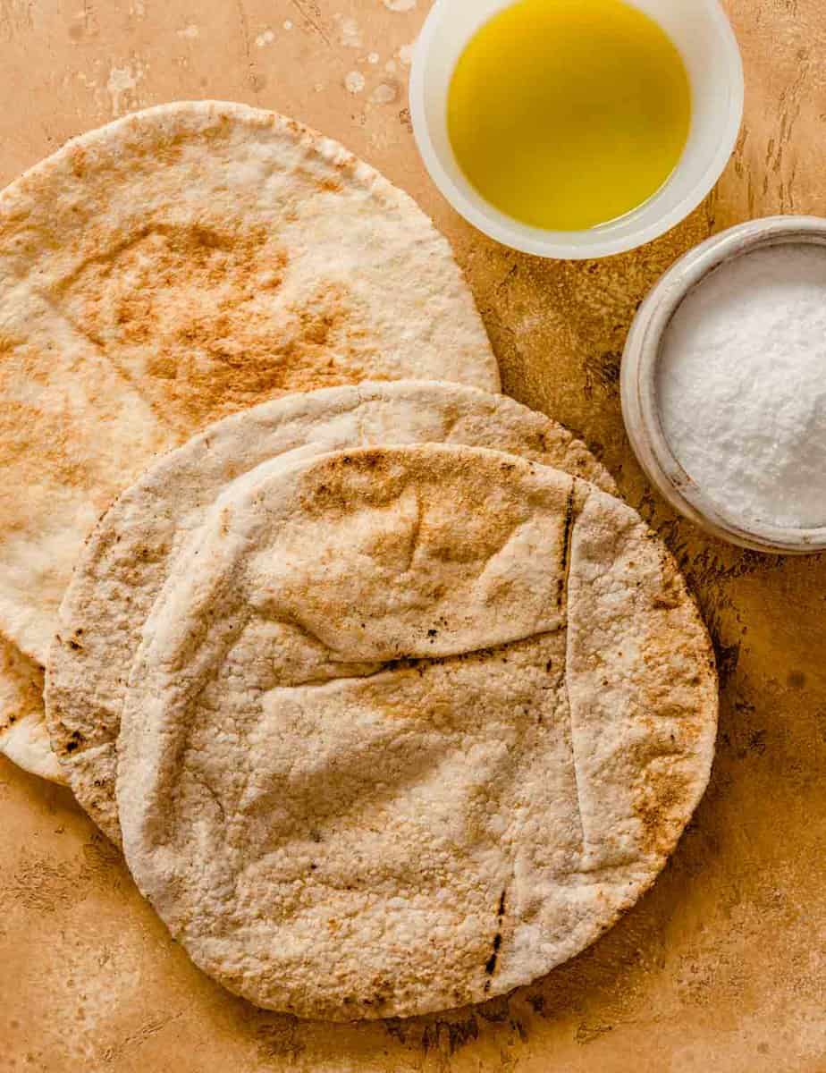 pita bread, oil and salt arranged on a counter