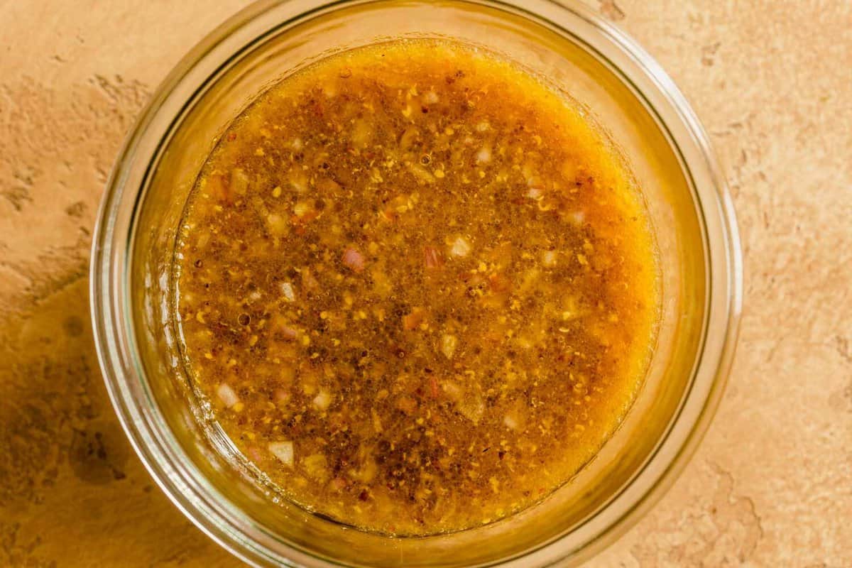 mustard vinaigrette in a glass bowl set on a yellow counter