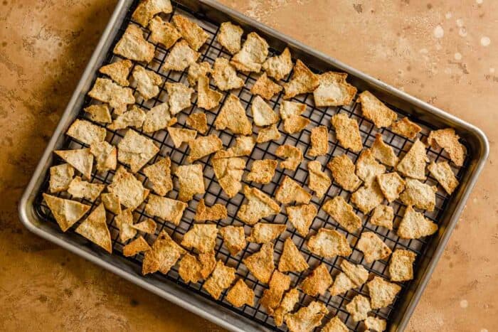 baked pita chips on a wire rack set inside a baking sheet
