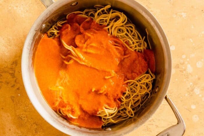 cooked ramen in a pot with an orange sauce poured over top