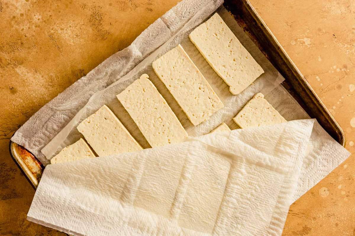planks of tofu on a baking sheet layered with paper towels