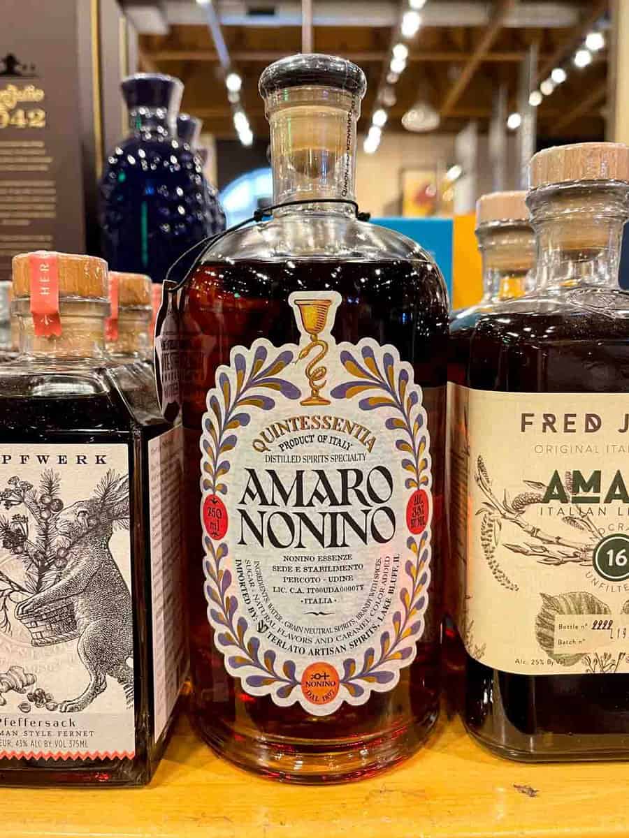 three bottles of amaro on a wood shelf