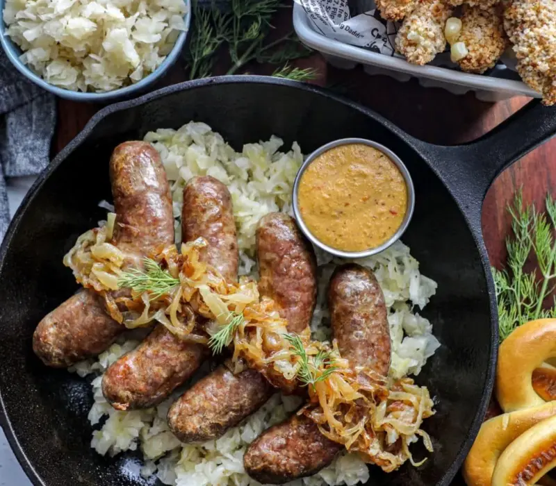 brats in a cast-iron skillet with a creamy sauce and sauerkraut