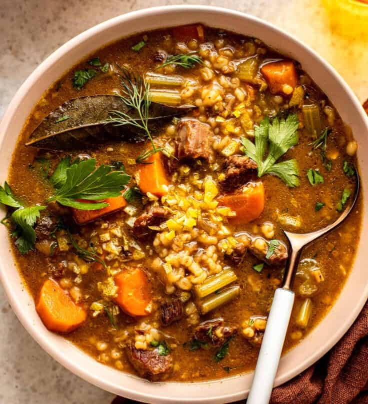 beef, barley and vegetable soup in a shallow white bowl