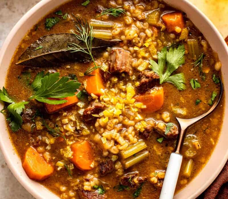 beef, barley and vegetable soup in a shallow white bowl