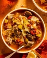 beef and cabbage soup with tomatoes in a shallow white bowl