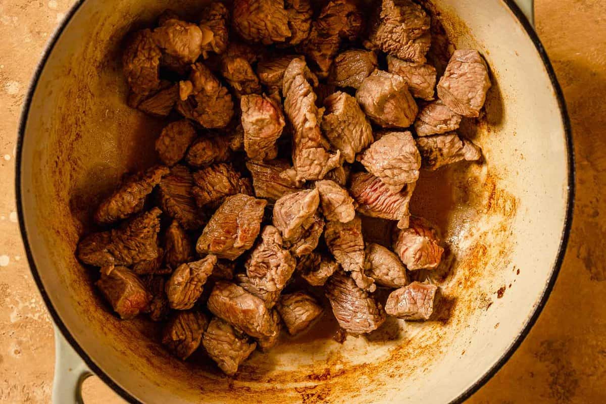 chunks of beef browning in a large Dutch oven