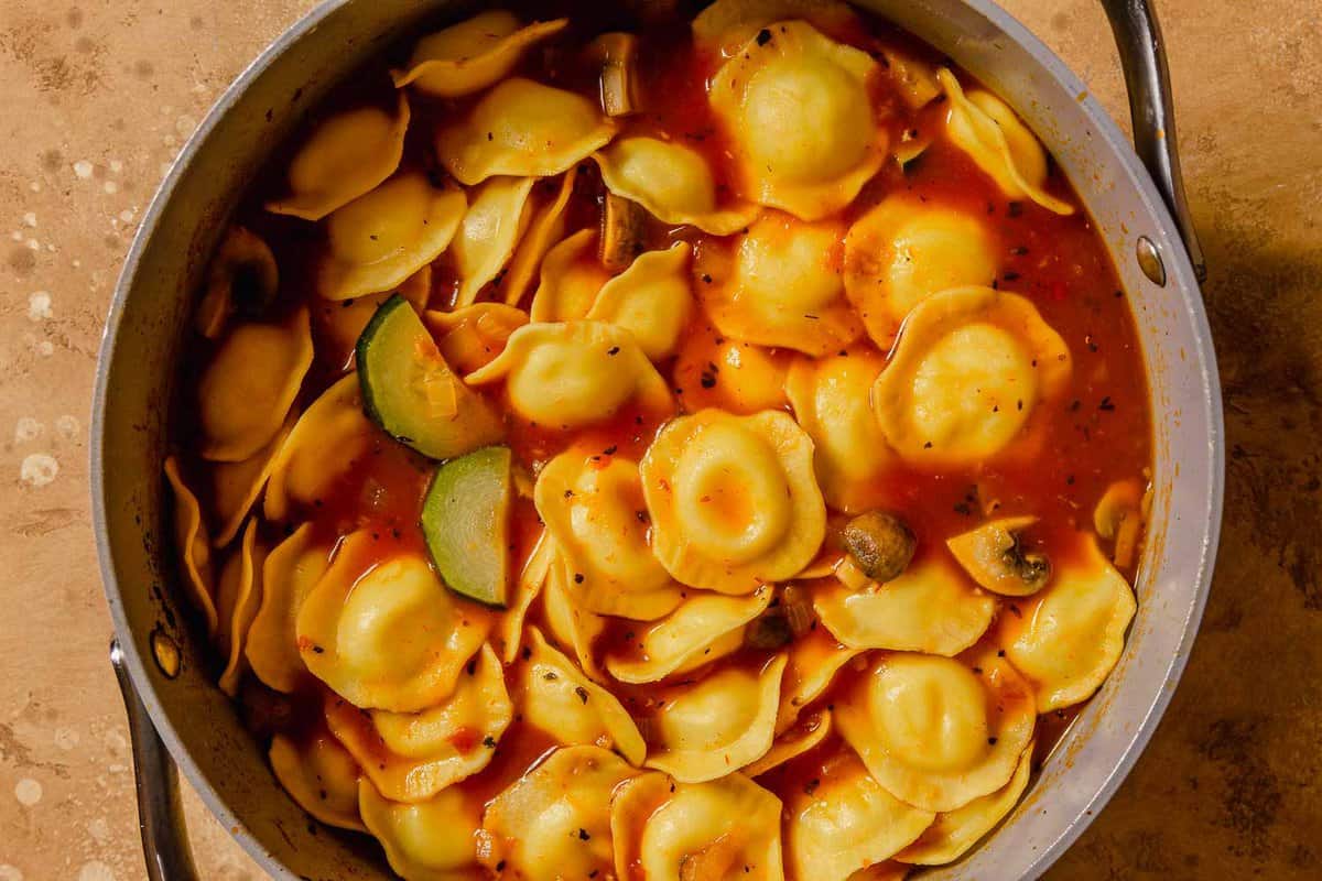 large pot with ravioli and zucchini in a tomato broth