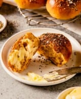 sweet potato dinner roll with butter spread on it on a white plate