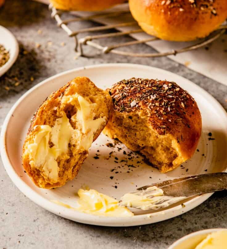 sweet potato dinner roll with butter spread on it on a white plate